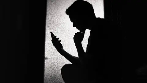 Getty Images Stock image of teenager with phone in silhouette