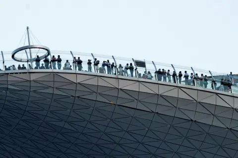 AFP Visitors looking at the view from the skypark of the 55-storey hotel tower of Marina Bay Sands in Singapore, 26 August 2010