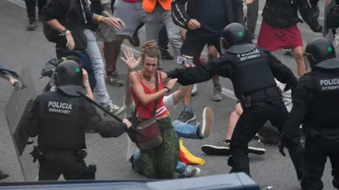 AFP Policemen hit a protester with batons outside El Prat airport in Barcelona