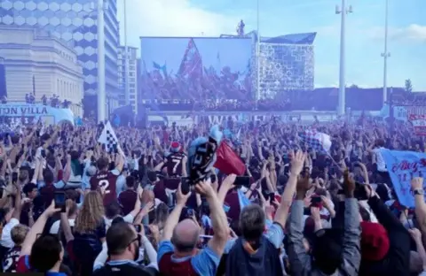 PA Thousands of fans celebrating in front of a large screen relaying scenes from the parade.