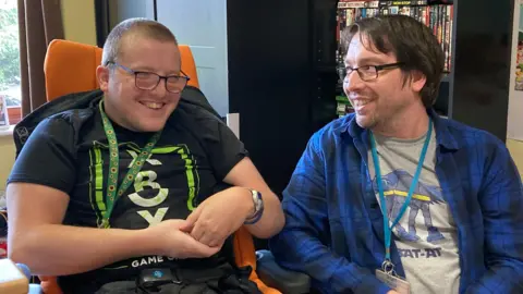 National Star College Xenon (left) and his carer David Stokes (right) laughing together in Xenon's room