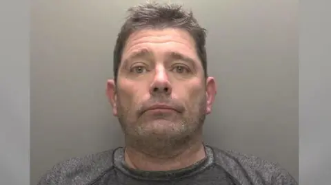 Humberside Police A police custody picture showing the head and shoulders of a man with short brown hair and stubble wearing a grey T-shirt against a grey backdrop.
