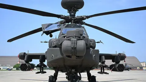 File image of an AH-64 Apache helicopter in a stationary position ahead of a US military parade