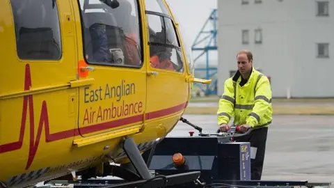 Getty Images Archive image of Britain's Prince William, The Duke of Cambridge (C) manoeuvres an air ambulance as he begins his new job with the East Anglian Air Ambulance