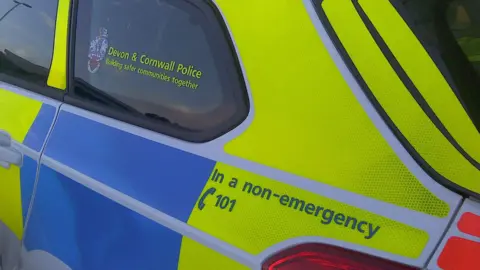 The blue and fluorescent yellow colouring on a Devon and Cornwall Police car.
A notice on the car also tells people to call 101 in a non-emergency. 