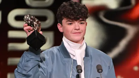 Getty Images Owen Cooper holding up his Bafta award