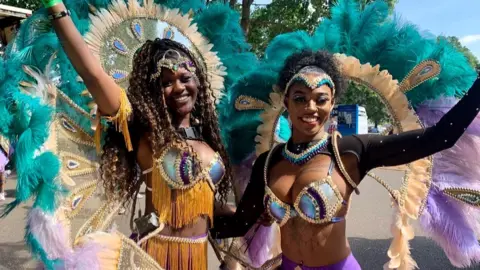 Two Caribbean carnival dancers in brightly coloured costumes.