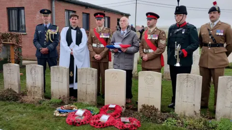 Ministry of Defence Lt Charles Cautherley's cousin Simon stands behind the new headstone at the ceremony