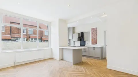 Stephen Tew Estate Agents The renovated, modern open plan living/kitchen space with a wood herringbone floor, white walls and a fitted kitchen in grey with a peninsula tucked into the corner