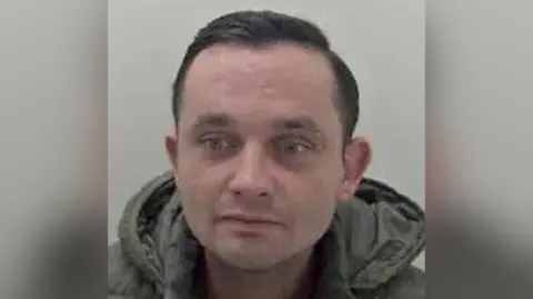 Kent Police A police mugshot of a man with short black hair and green hoodie. 