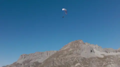 Turner Twins A blue sky is seen with the twins in the air with the paraglider above the French Alps