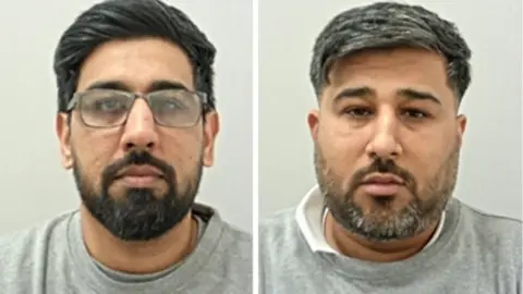 Kashif Mehdi (L) has dark hair and beard with spectacles. Rizwan Mehdi (R) has greying dark hair and beard. Both are wearing grey prison sweat shirts.