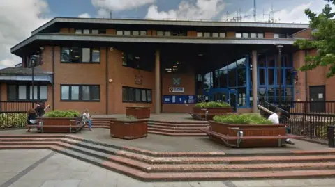 Google The three-storey brick-built council building in St Albans, with small windows. There are blue window frames around the entrance of the building to the right, and steps leading up to it. The council logo is visible on the building to the left of the entrance. There are planters on the steps.