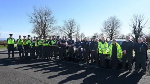 Wiltshire Police A large group of police officers standing outside in a row in front of some police vehicles