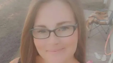 Family photo Cerys Rees smiling in front a chair with a blanket on 
