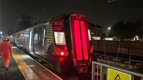 Network Rail The image shows a train on railway tracks. The train appears is a 380 electric EMU. It has a sleek body with large windows along the sides, and the front section is rounded..