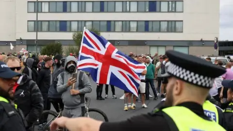  PA/Hollie Adams Protestors hold a GB-flag outside the Holiday Inn Express