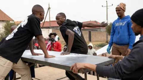 James Oatway / Reuters A contestant prepares to deliver a blow during a slap fighting competition in Kagiso township, west of Johannesburg, South Africa August 4, 2024