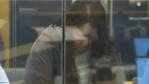 Hakyung Lee, in a gray jacket and with her head bowed, in the dock at a court in Auckland, New Zealand