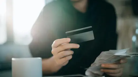 Getty/D3sign A stock image of a woman holding a credit card