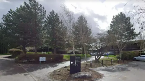 Google Maps Front of the golf complex, with sign, trees, parked cars and clubhouse building in the background