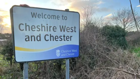 A large white and black road sign saying "Welcome to Cheshire West and Chester".