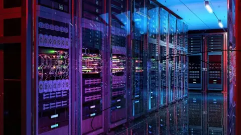 A brightly lit data centre corridor filled with rows of tall server racks enclosed in glass cabinets. Multicoloured cables and LED lights glow in purple, blue, and red tones, reflecting off a glossy floor. Cooling panels and network equipment line both sides, creating a symmetrical, high-tech environment. Some black scribble marks appear over parts of the image.