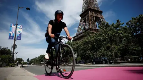 Getty Images  A man riding a bike across Paris with the Eiffel Tower in the background