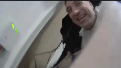 Northamptonshire Police Finnlayson with short dark hair laughing, captured on bodycam footage. 