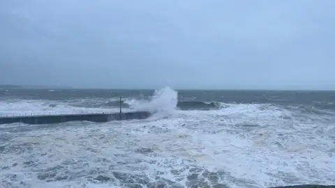 A sea view from Porthleven in Cornwall. The waves are crashing against the breakwater.