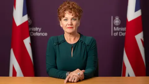 Ministry of Defence Former Wrexham MP Sarah Atherton sitting at a desk in front of two Union flags and Ministry of Defence logos when she was appointed a defence minister in 2002