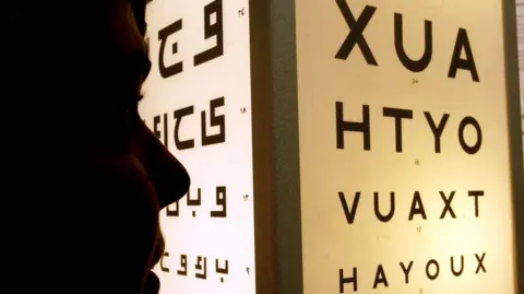 A silhouette of a person reading an eye test chart
