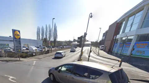 The entrance to a T junction with a crossing and traffic lights, with a Lidl supermarket nearby