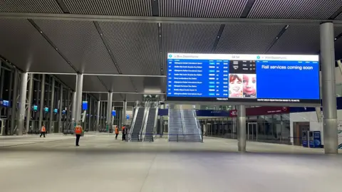 The inside of Grand Central Station in Belfast. To the right of the image is a large notice board with the bus timetable. 