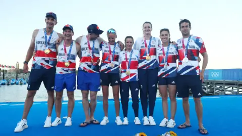 Eight of Great Britain's sailing team are smiling at the camera. 
