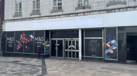 Simon Thake A large closed shop unit with black doors.