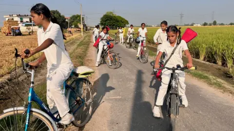 BBC The girls seen arriving for practice on their bikes