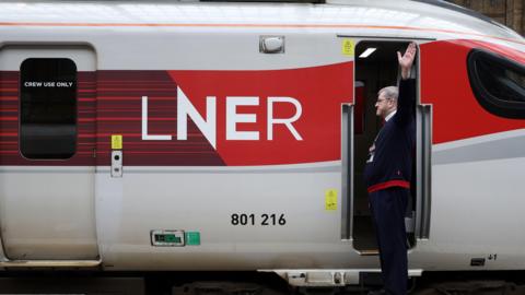 An LNER staff member standing next to a train