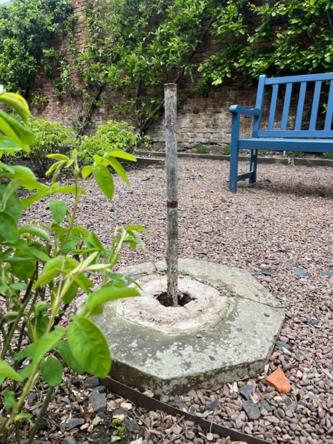 Paxton House A stone base and pole where once a sundial stood. There is a blue bench in the background.