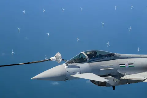 Leon Neal / Getty Images Wind turbines are seen in the distance as an RAF Typhoon fighter jet is refuelled in-flight over the North Sea