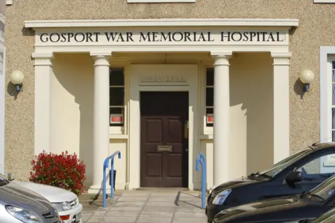 PA Media The front entrance of Gosport War Memorial Hospital showing stone pillars with the name above