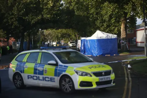 PA Media The scene outside Ascot Drive police station in Derby where a man was taken to hospital after being shot. 