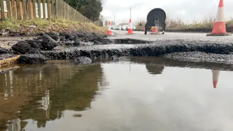 Another view from the pothole. A queue of cars is in the distance.