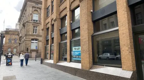 The exterior of Imperial Buildings, 9 Dale Street, in Liverpool. It is a modern office building of brick and glass, and Liverpool Town Hall can be seen in the background of the photograph. 