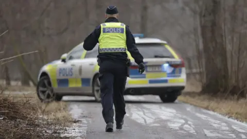 AFP A police officers walks towards a police vehicle near the Risbergska School in Orebro, Sweden, on February 4, 2025, following reports of a serious violent crime. 