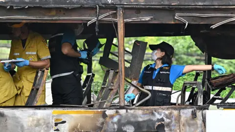 Getty Images Rescue workers and police investigate a burned-out bus carrying students and teachers outside Bangkok on October 1, 2024.