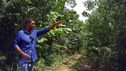 Fabricio pointing at a tree in the forest