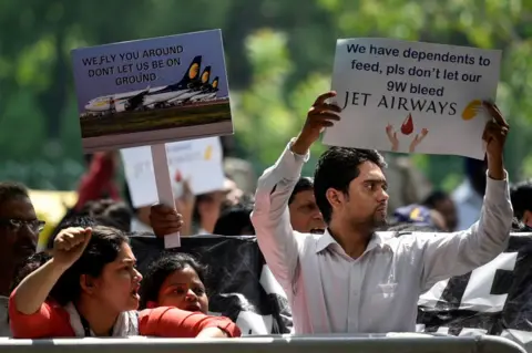 Getty Images Jet Airways employees hold placards as they raise slogans during a protest against delayed salaries and the current shutdown crisis outside Rajiv Gandhi Bhawan at Jor Bagh on May 21, 2019 in New Delhi, India.