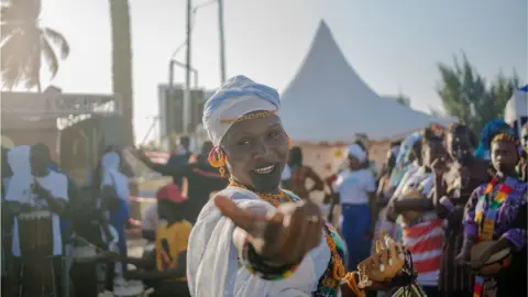 AFP A woman dressed in white smiling and holding her hand out
