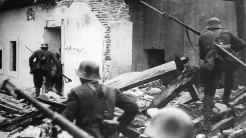 Getty Images Nationalist troops loyal to General Franco advance through the debris of houses at Madrid